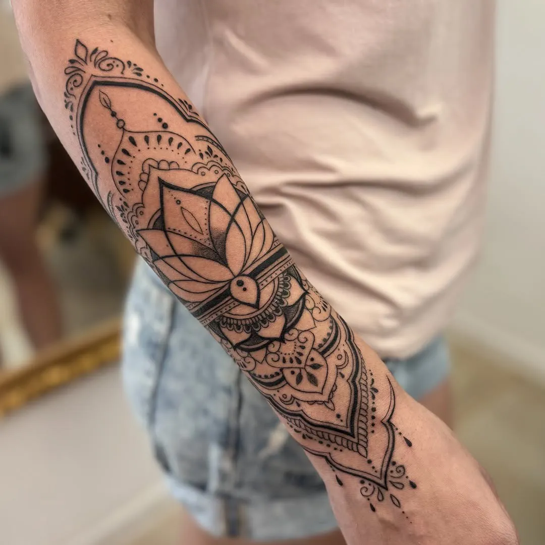 Mandala ar lotosu un ornamentu visā apakšdelma garumā